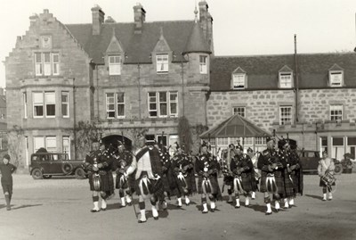 Dornoch Pipe Band parading in front of the Sutherland Arms Hotel 1930's