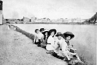 Six young ladies sitting on a river bank