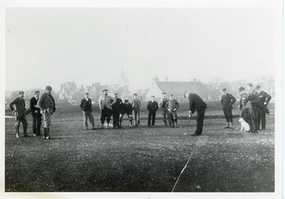 Golfer with audience of males and two dogs