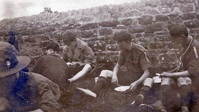 Scouts eating sitting against a wall