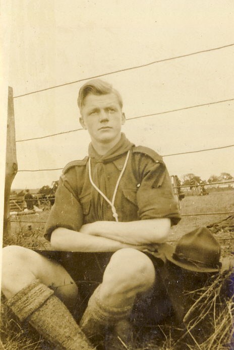 A scout sitting against a wire fence
