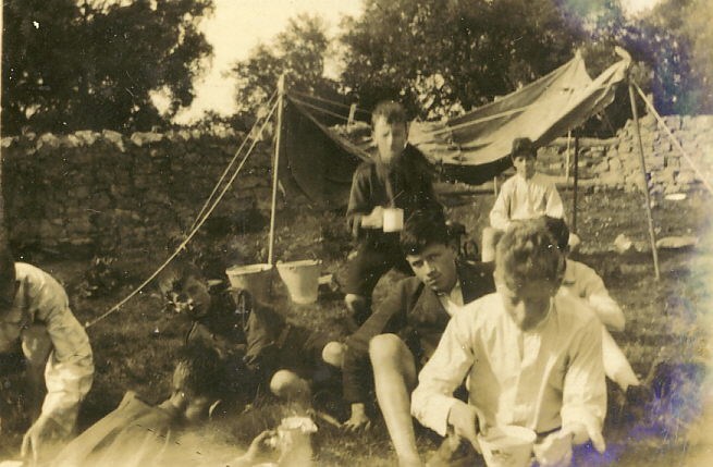 Scouts at tea with camp fire shelter in background