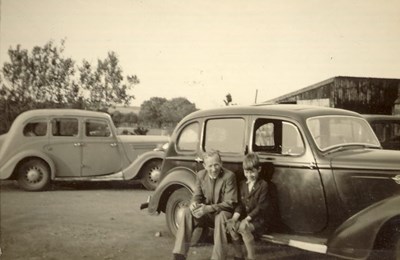 Man and Boy sitting on the running board of a car