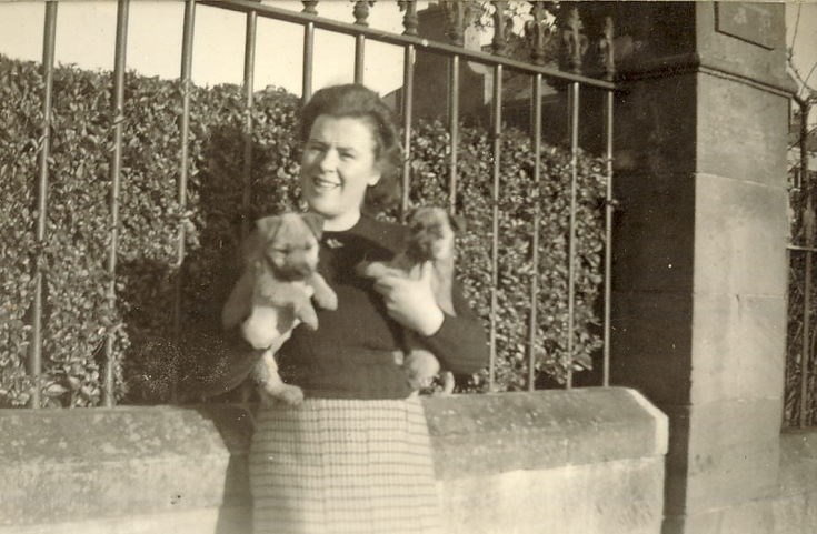 Lady holding two puppies, outside (probably) 