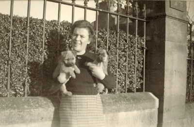 Lady holding two puppies, outside (probably) 