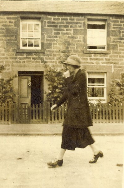 Lady walking in front of a house