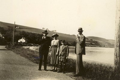 Two men, a woman, and a boy standing in front of a loch