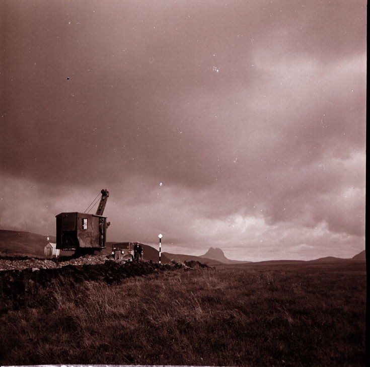 Road workers, car and potholes with Suilven in the background
