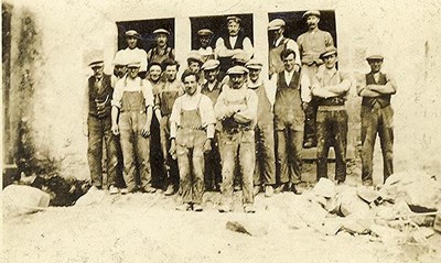 Group of 20 men outside a sawmill building